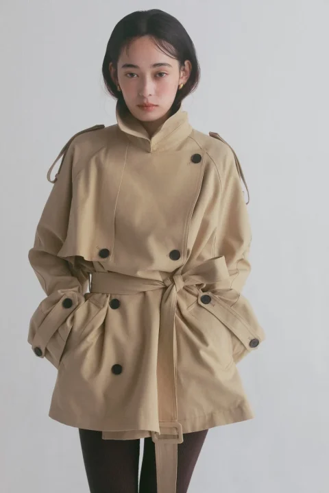 ベージュのショート丈トレンチコートの女性