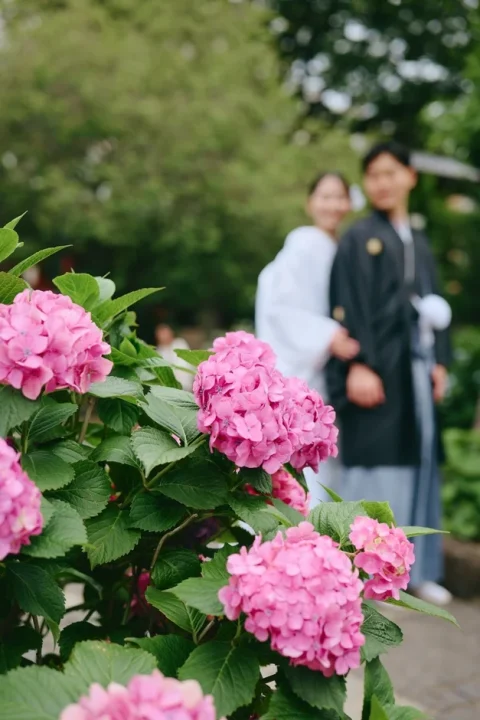 紫陽花が咲く庭園で和装の新郎新婦が笑顔で立つ様子