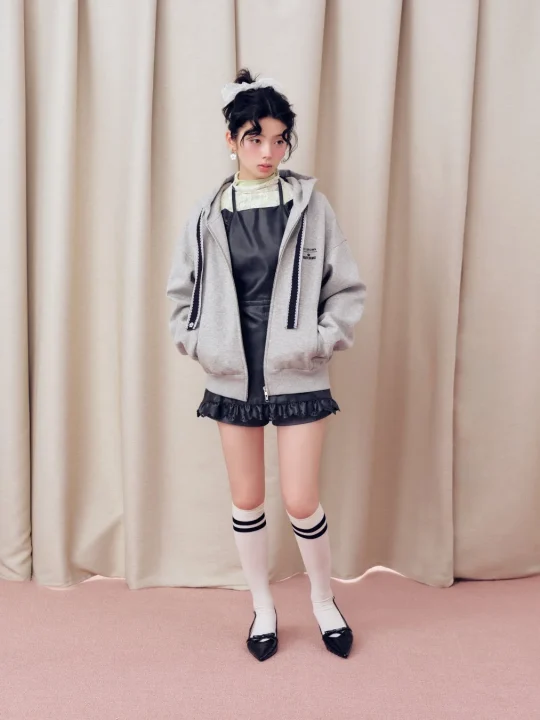 グレーのパーカー、黒いレザーショートパンツ