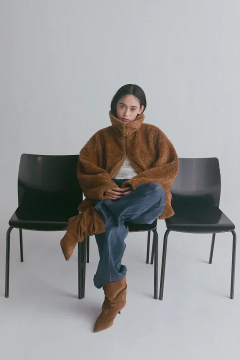 茶色のボアジャケットとジーンズの女性