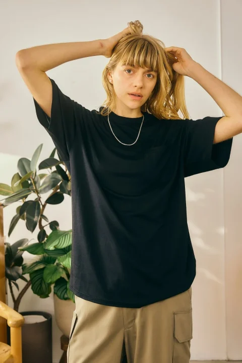 黒いTシャツとカーキ色のカーゴパンツを着用した金髪の女性