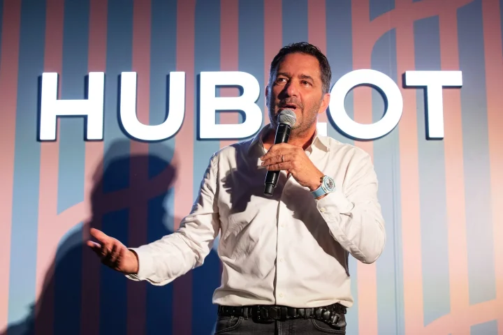 HUBLOTのロゴを背景にマイクを持ってスピーチをする男性