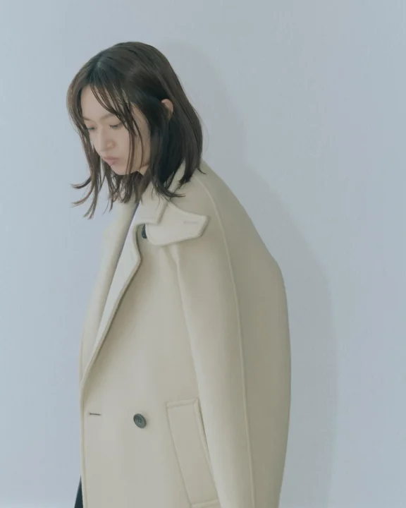 クリーム色のダブルブレストコートの女性
