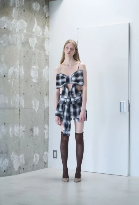 チェック柄のリボンモチーフのトップスとミニスカートを着た女性モデル