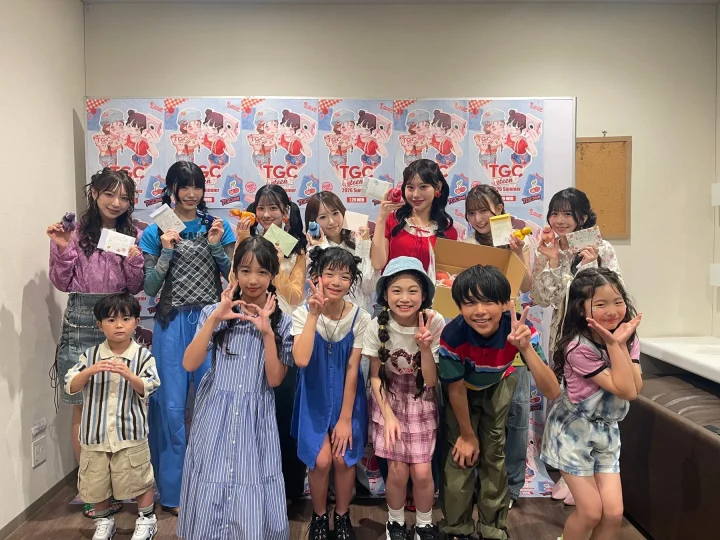 イベント「TGC teen Summer」のポスターを背景に、多くの子供たちと数人の若い女性が楽しそうにポーズをとっている集合写真です。