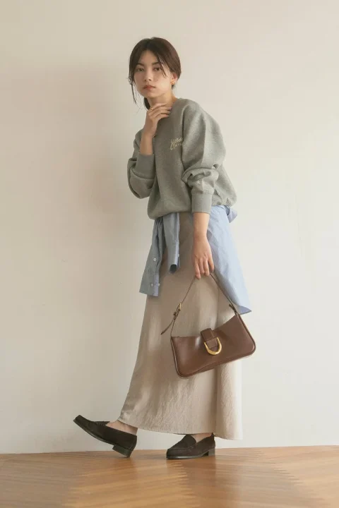 グレーのスウェットにベージュのロングスカートを合わせた女性