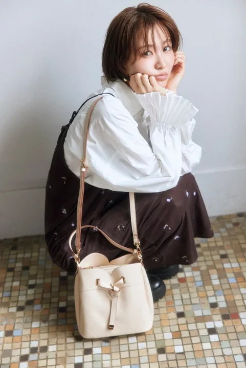 ベージュのバッグを持つショートヘアの女性
