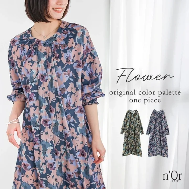 笑顔の女性が花柄の長袖ワンピースを着用している画像。ネイビー、ピンク、ブルーの花柄が特徴で、別カラーのワンピースも紹介されており、アパレルブランドn'Orの商品広告です。