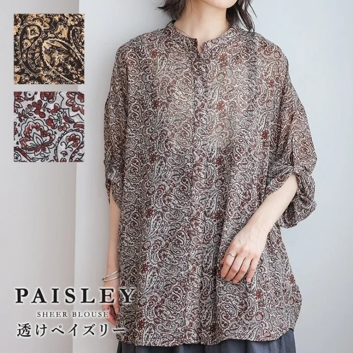 ペイズリー柄のシアーブラウスを着用した女性のファッション画像です。ブラウン系の透け感のある素材が特徴で、スタンドカラーとロールアップされた七分袖がデザインのポイントとなっています。