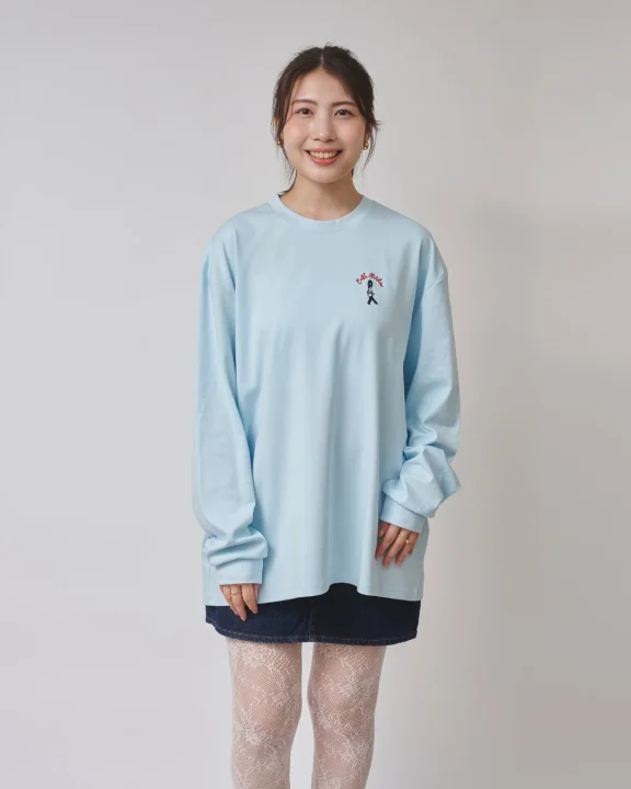 水色のオーバーサイズ長袖Tシャツにデニムミニスカート、白いレースタイツを合わせた女性