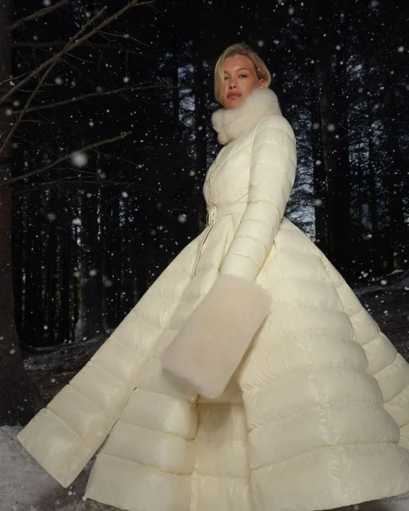 雪が降る夜の森で白いロングコートをまとった女性