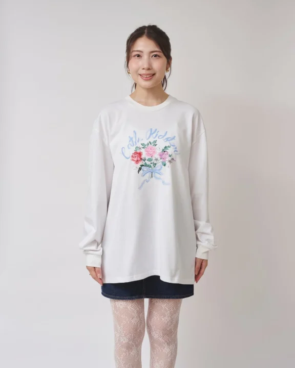 白い長袖Tシャツとデニムスカート、レースタイツを着用した若い女性