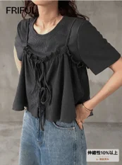 ギャザーと紐のデザインが特徴的な黒いトップスとデニム