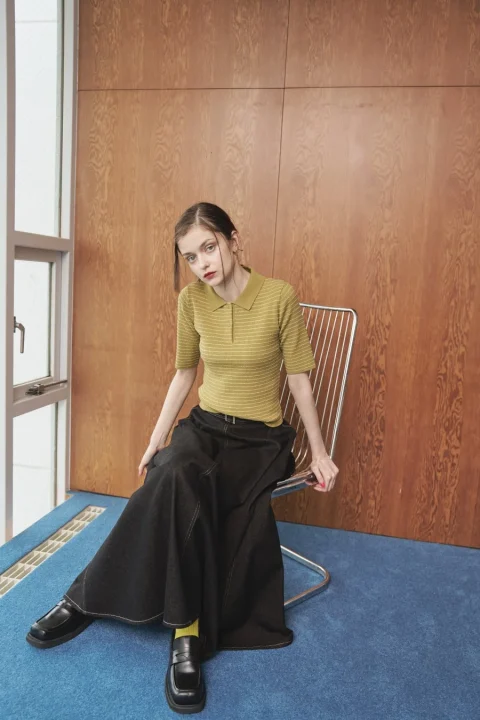 緑色のボーダー柄ポロシャツと黒いロングデニムスカートの女性