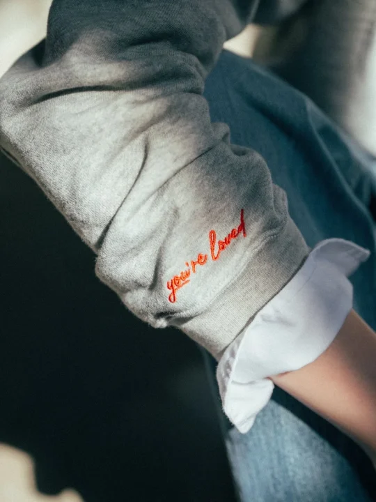 グレーのスウェットに刺繍された「you're loved」のメッセージ