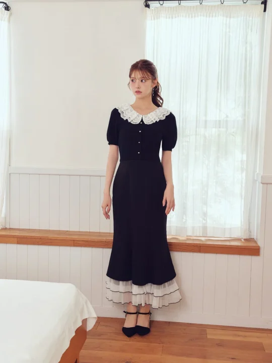 白いレース襟と裾のフリルが特徴的な黒いワンピースを着た女性