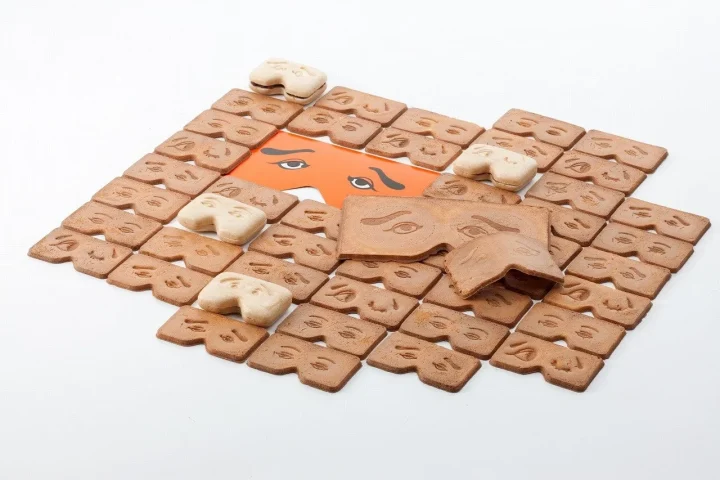 目や眉毛の形をしたクッキーやビスケットが多数並べられた画像