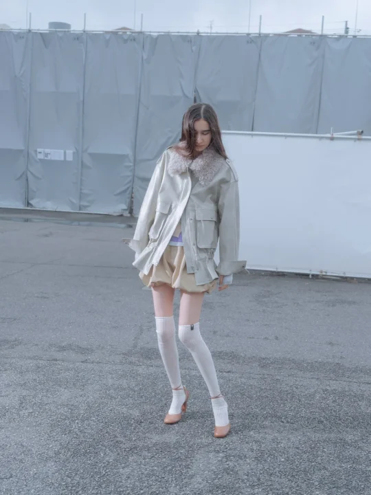 グレーのファーカラー付きジャケットとベージュのショートパンツのモデル画像