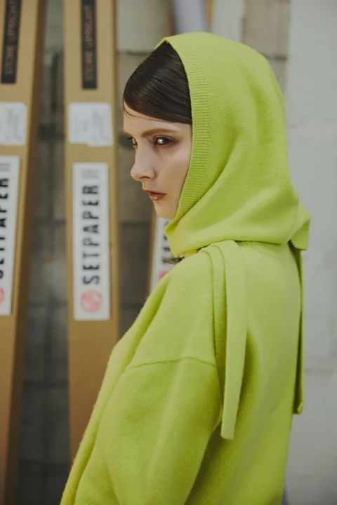 ライムグリーンのフード付きニットの女性