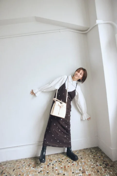 ベージュのバケットバッグを持つショートヘアの女性（全身）