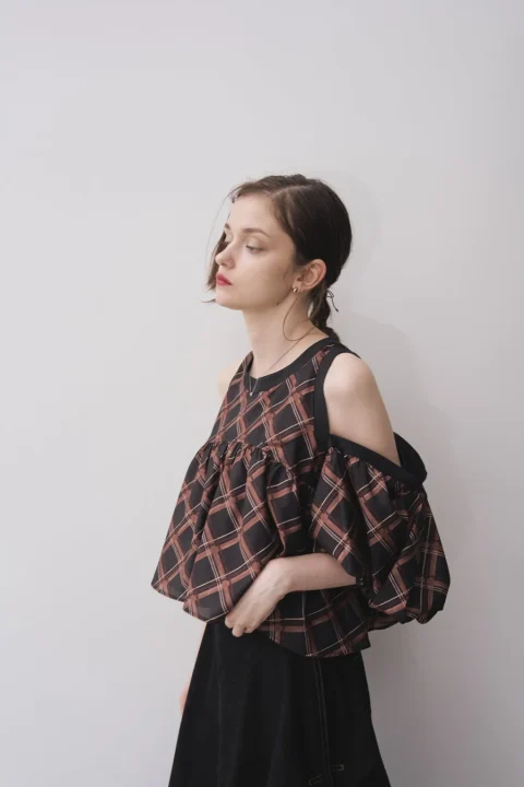 チェック柄のオフショルダートップスと黒いスカートの女性