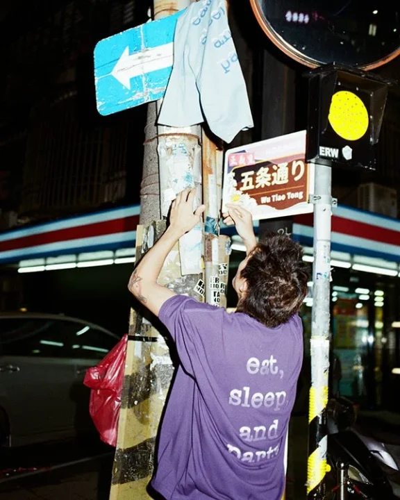 夜の街角で標識に手を伸ばす人物