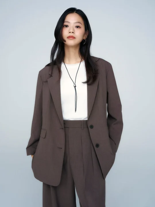 ブラウンのオーバーサイズジャケットとワイドパンツのスーツを着用した女性