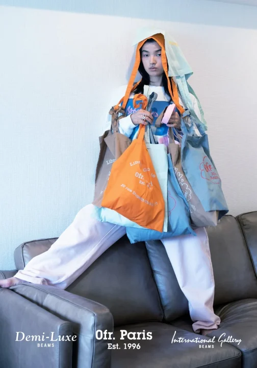 たくさんのカラフルなトートバッグを身につけてポーズをとる人物