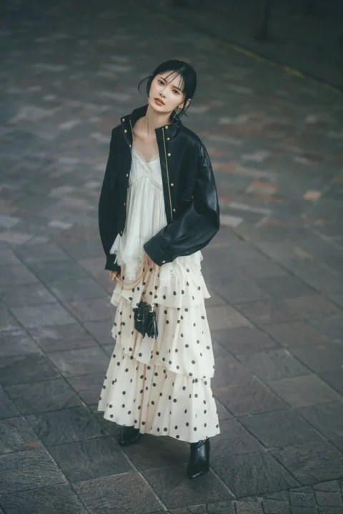 レザージャケットとドット柄ティアードスカートを着用した女性