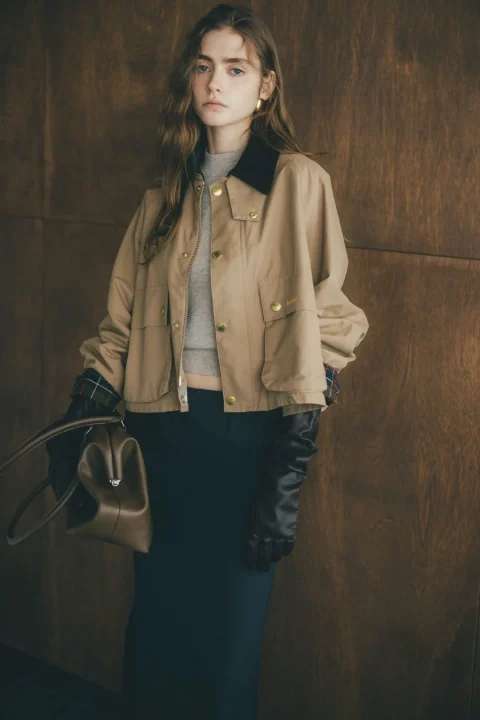 ベージュのショートジャケットとグレーのニットを着用した女性
