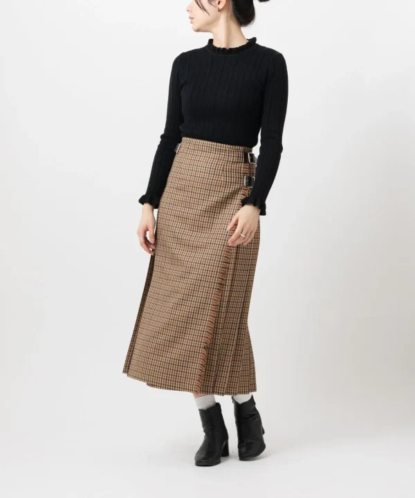 黒いリブニットのフリルネックセーターとブラウン系のチェック柄ロングスカートを着用した女性の全身コーディネート