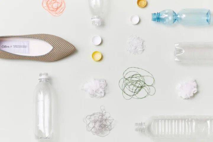 再生プラスチック素材で作られた靴と、使用済みのペットボトルやリサイクル素材が並べられた様子