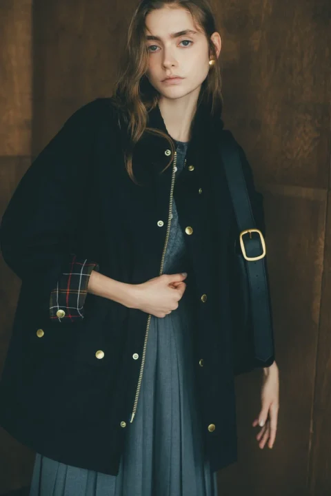 黒いジャケットとグレーのプリーツスカートを着た女性