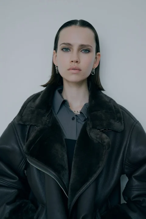 ダークカラーのムートンジャケットを着用した女性のポートレート。