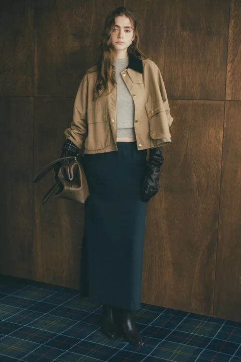 ベージュのショートジャケットとロングスカートを着用した若い女性