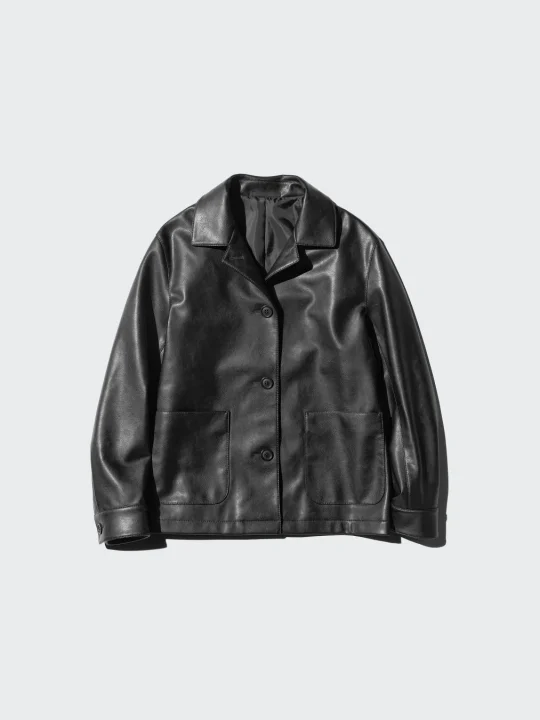 明るい灰色の背景に置かれた、黒いフェイクレザーのジャケットです。襟付きで、フロントには3つのボタンと2つのパッチポケットが付いています。カジュアルな服装に適したアウターです。