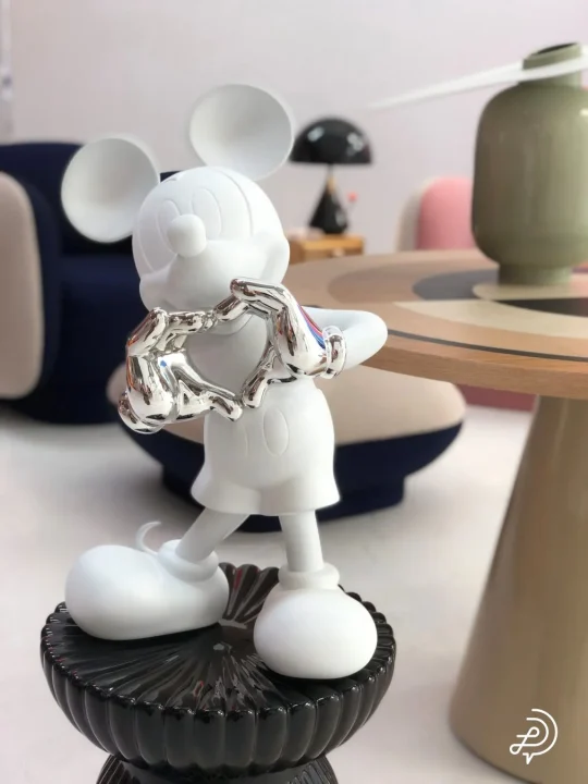 白いミッキーマウスのフィギュアが銀色の手でハートマークを作っている様子