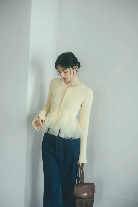 ぺプラムカーディガンとワイドデニムパンツを着用した女性