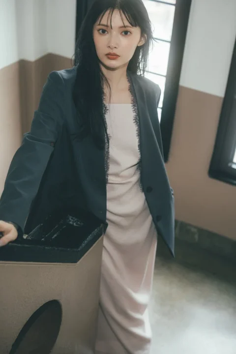 ダークグレーのジャケットとピンクベージュのレース付きドレスを着用した女性