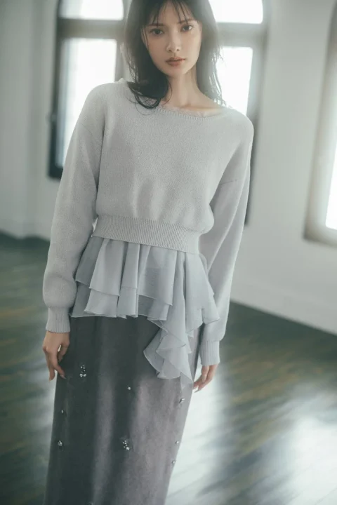 ライトグレーのニットとダークグレーのスカートを着用した女性